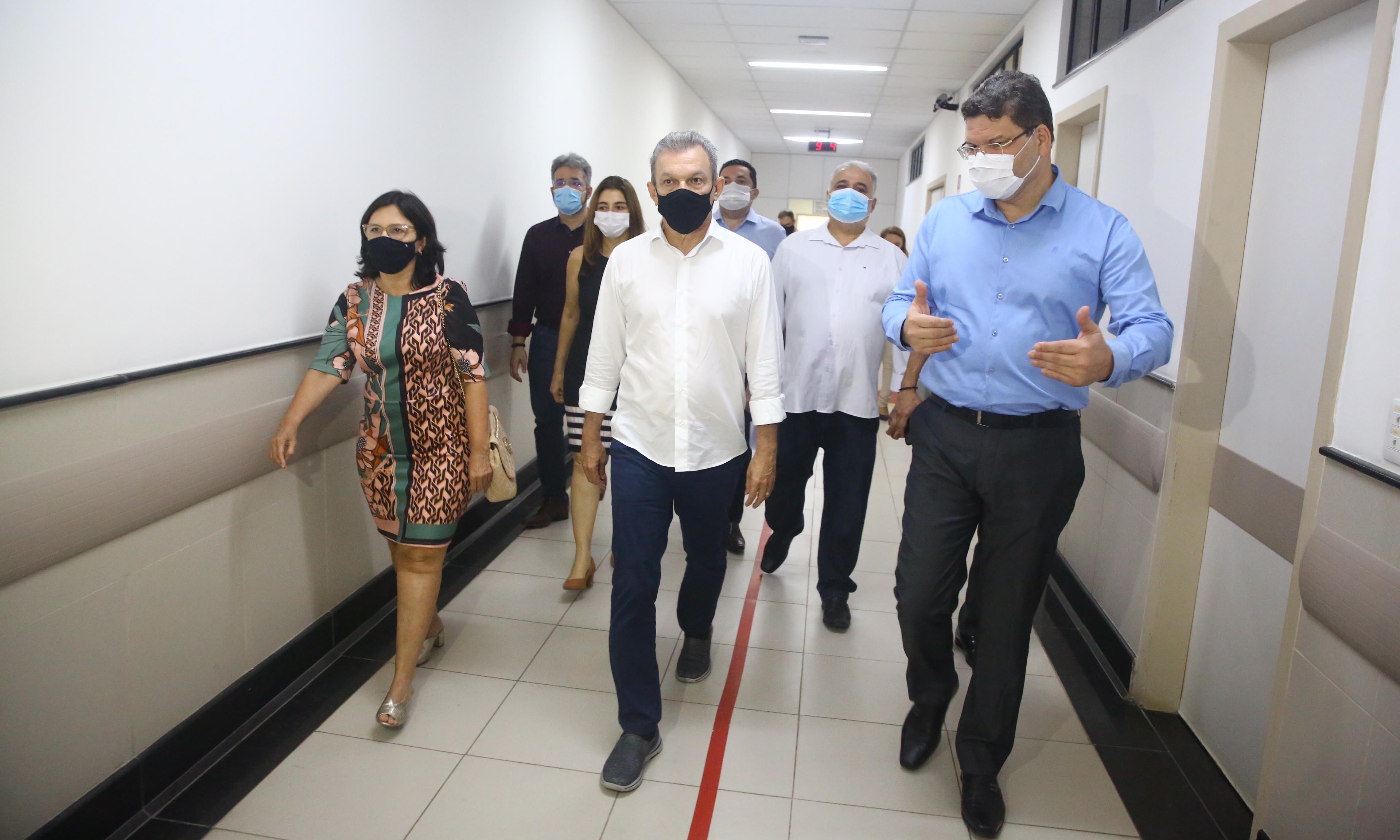 Sarto de máscara caminhando por corredor do Hospital da Mulher ao lado da secretária Ana Estela e mais pessoas